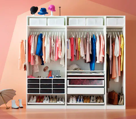 Белый гардероб ПАКС без дверей, в котором видны разноцветные предметы одежды, обувь и головные уборы, а также небольшие коробки для хранения.